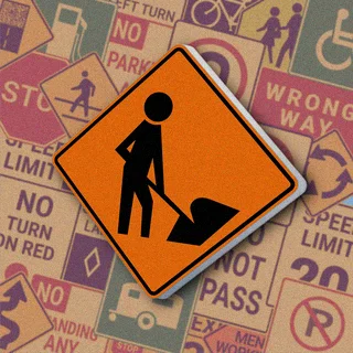 Оранжевый ромб с черным силуэтом человека с лопатой. Знак "Road work ahead" предупреждает о проведении дорожных работ впереди